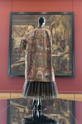 a tapestry swing coat in front of a wall tapestry